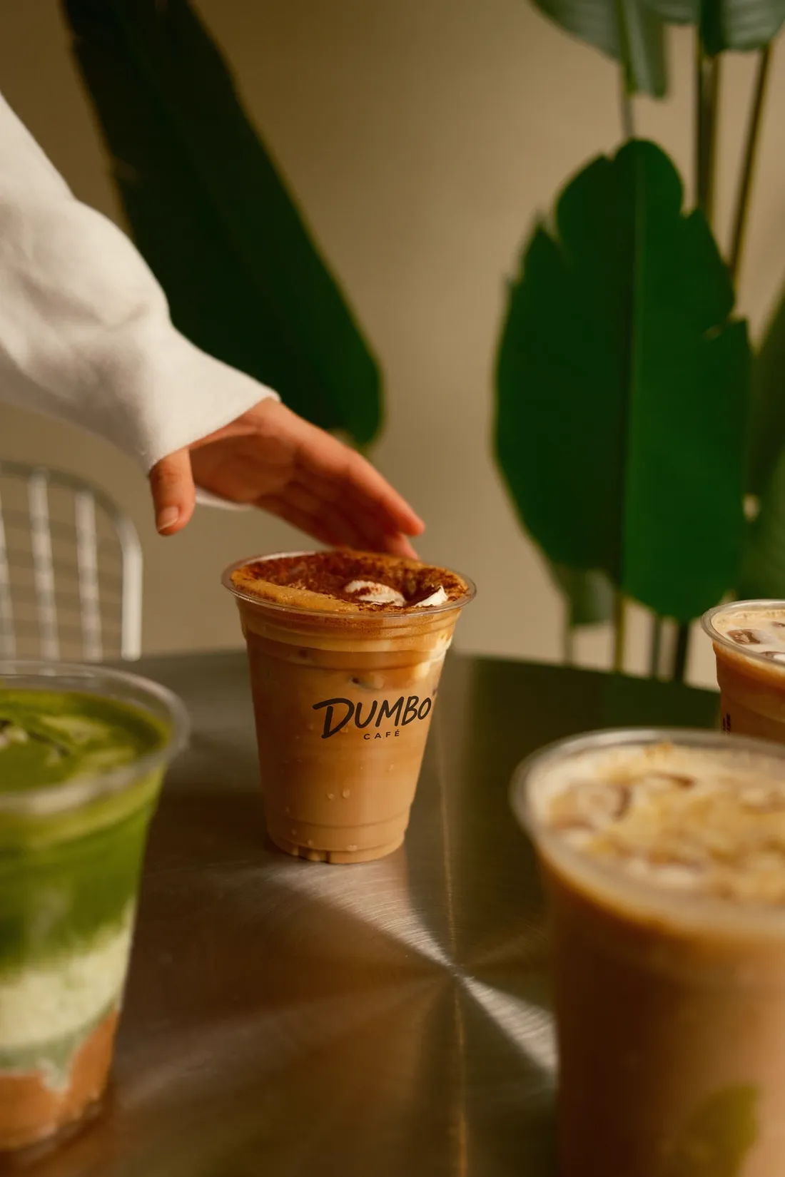 Hand reaching for an iced coffee with a Dumbo cup